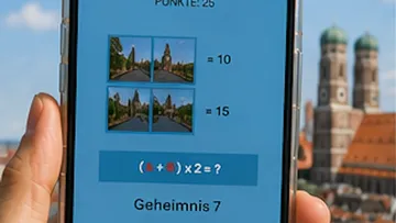 Smartphone displaying math puzzle against cityscape backdrop.