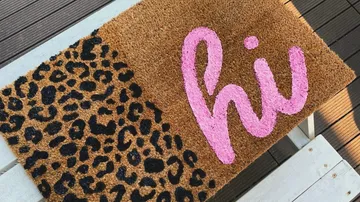 Doormat with leopard print and pink "hi" text.