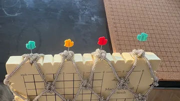 Stecknadeln sichern Strickmuster auf Messbrett.
