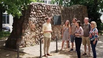Gruppe hört zu an historischer Steinmauer.