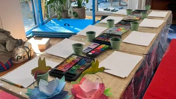 Tisch mit Kunstmaterialien und Papieraufbau.