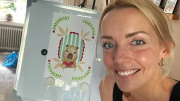Frau lächelt neben Bärenzeichnung.