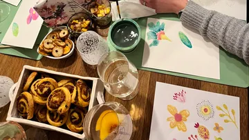 Person malt, umgeben von Snacks und Getränken.