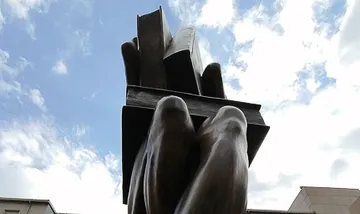 Skulptur einer Hand mit Büchern, im Freien.