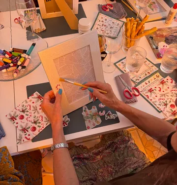 Person decorating picture frame at crafting table.