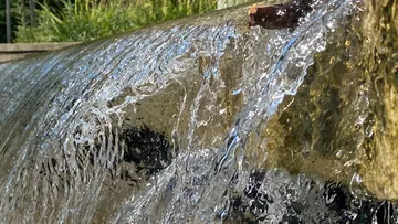 Wasser fließt über Steinkante draußen.