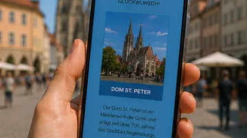 Hand hält Handy mit Dom St. Peter Anzeige.