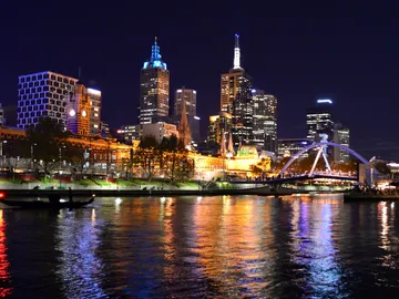 Skyscrapers reflect in water, night view of Melbourne.
