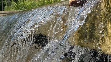 Wasser fließt über Steinkante draußen.