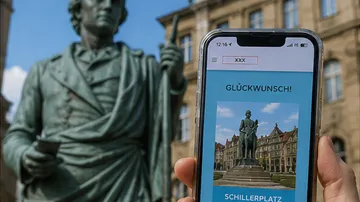Statue next to phone displaying Schillerplatz.