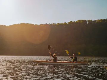 Zwei Personen paddeln gemeinsam in einem Kajak auf einem See.
