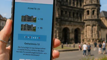 Hand hält Handy mit App, Ruinen im Hintergrund.