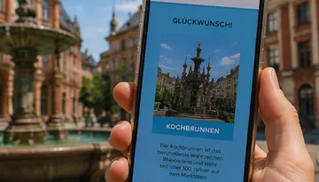 Hand hält Handy mit Brunnenfoto.
