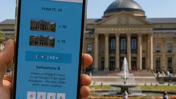 Hand hält Smartphone vor historischem Gebäude.