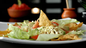 Salat mit Chips auf weißem Teller.