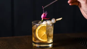 Cocktail mit Orangenscheibe und Garnitur.