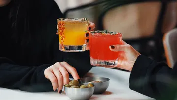 Zwei Personen stoßen mit Cocktails an.