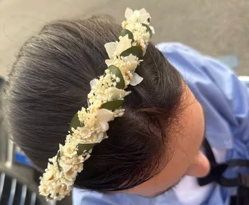 Floraler Haarreif auf dunklem Haar im Freien.
