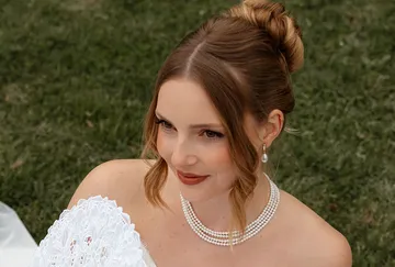 Bride smiling outdoors in garden setting.