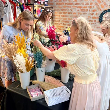 Frauen arrangieren bunte Blumen auf Tisch, drinnen.