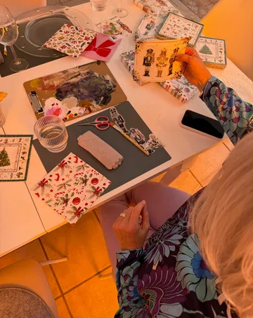 Person crafting holiday cards on a table.