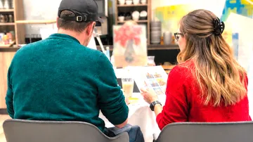 Mann und Frau sitzen, betrachten Broschüre drinnen.
