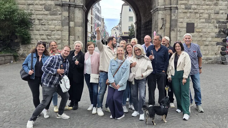 Group of people posing under stone archway.