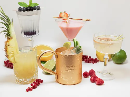 Colourful cocktails with fresh fruit are on a table.