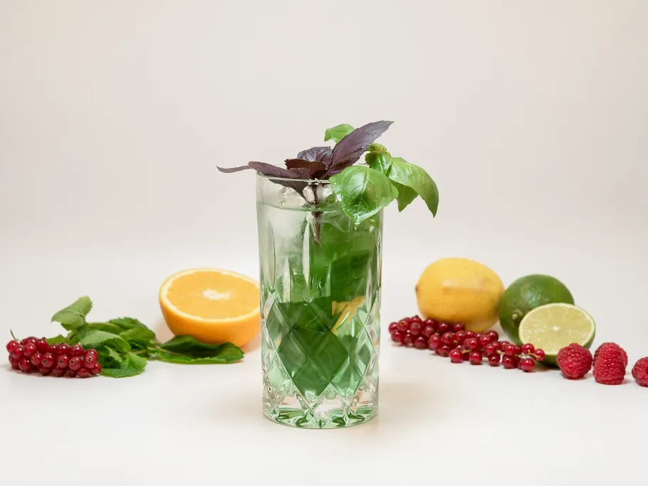 A glass with a cocktail and fresh fruit next to it.