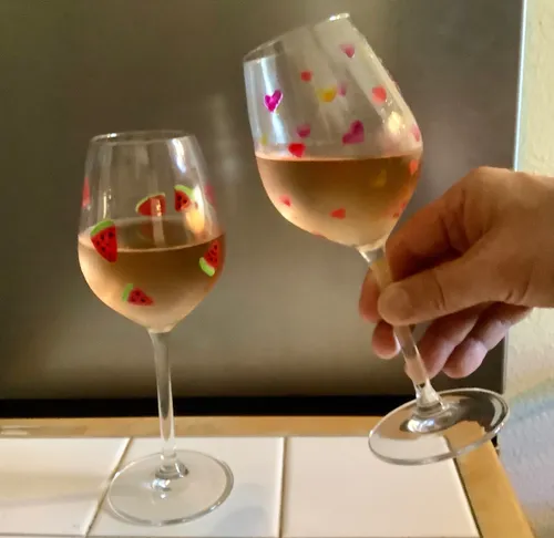 Two wine glasses clinking, kitchen background.