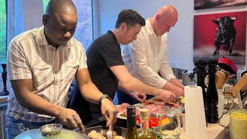 Three men preparing food in a kitchen.