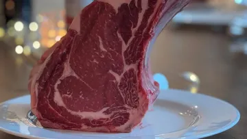 Raw steak standing upright on plate.