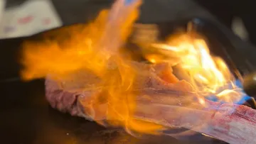 Steak on fire in kitchen setting.
