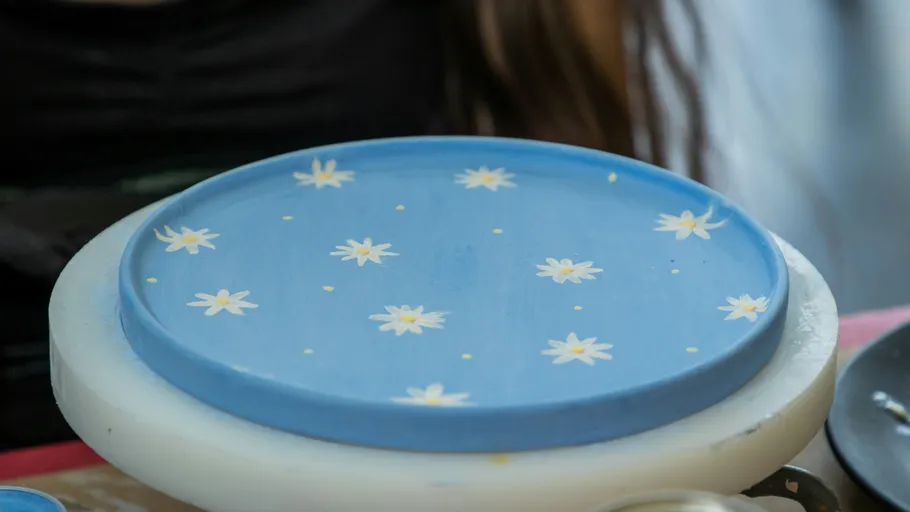 Pottery wheel holding blue floral plate.