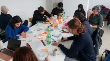 People writing at a table in a bright room.
