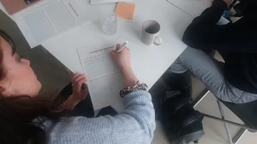 Person writing at a desk in meeting.