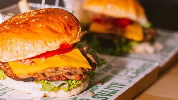 Burger mit Käse und Salat auf Tablett.