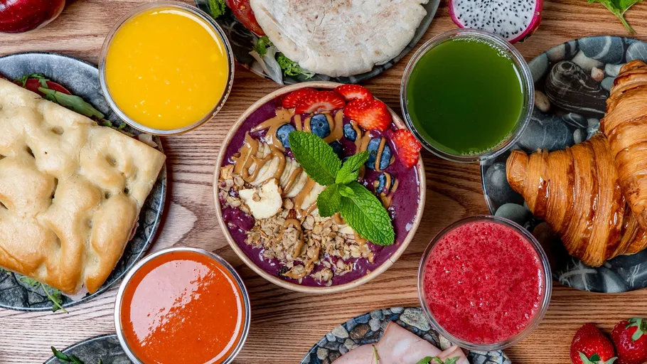 Frühstückstisch mit Smoothiebowls und Gebäck.