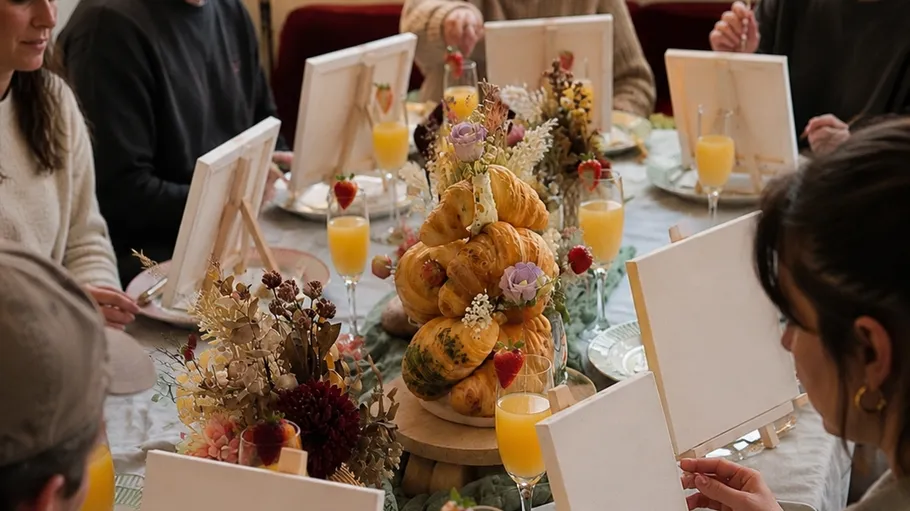 People painting at table with pastries.