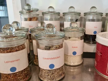 Glass containers with spices stand on a work surface.