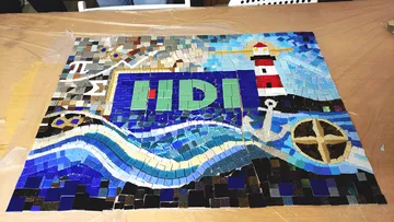 Mosaic featuring lighthouse, waves, and abstract designs.