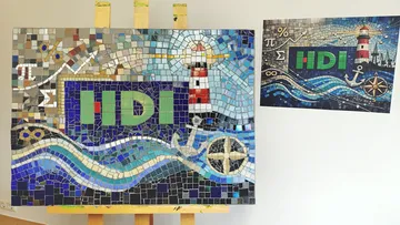 Mosaic of lighthouse and lettering on easel.