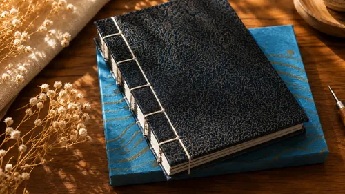 Japanese notebooks on wooden desk, dried flowers.