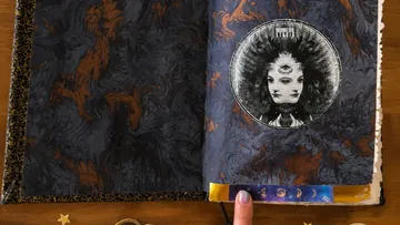 Finger pointing at celestial-themed book page.