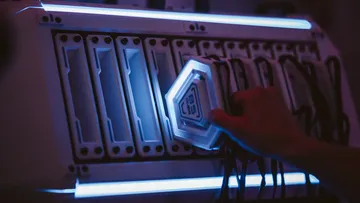Hand steckt Gerät in leuchtendes Server-Rack.