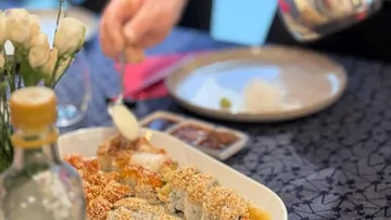 Person serving sushi in a cozy dining setting.