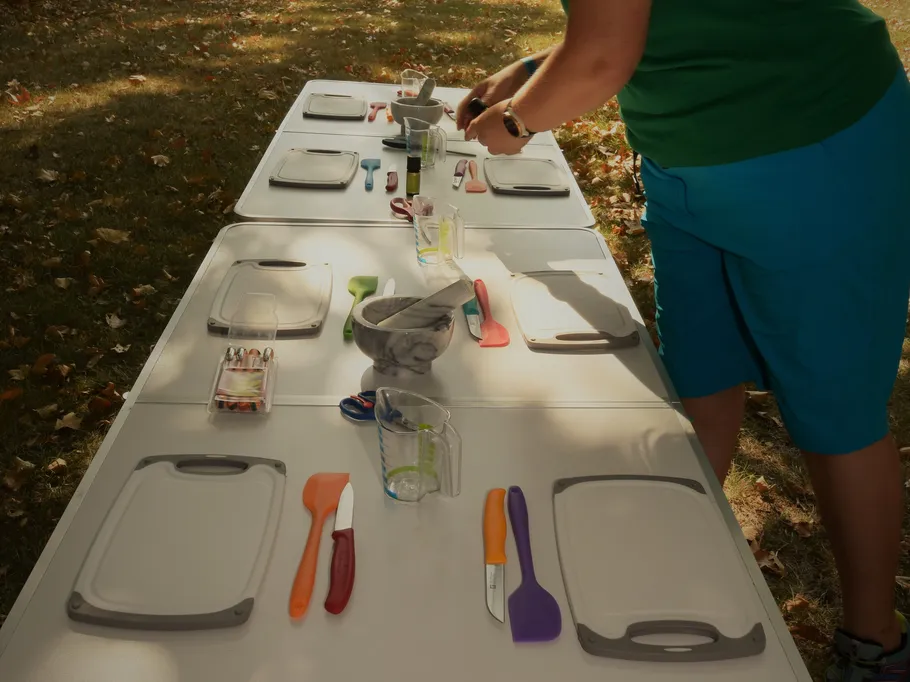 Table set with outdoor cooking utensils, person working.