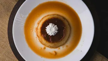 Flan-Dessert mit Sahne auf weißem Teller.