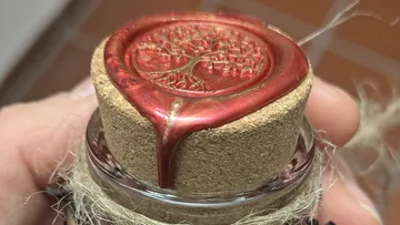 Wachssiegel auf Flaschenkorken mit Baumdesign.