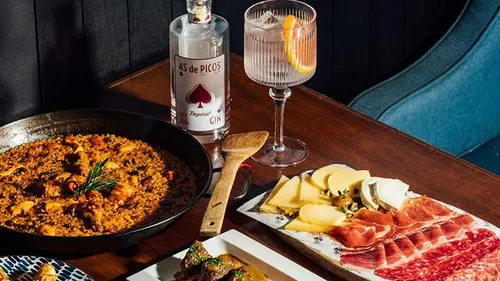 Paella und Gin auf einem Holztisch.